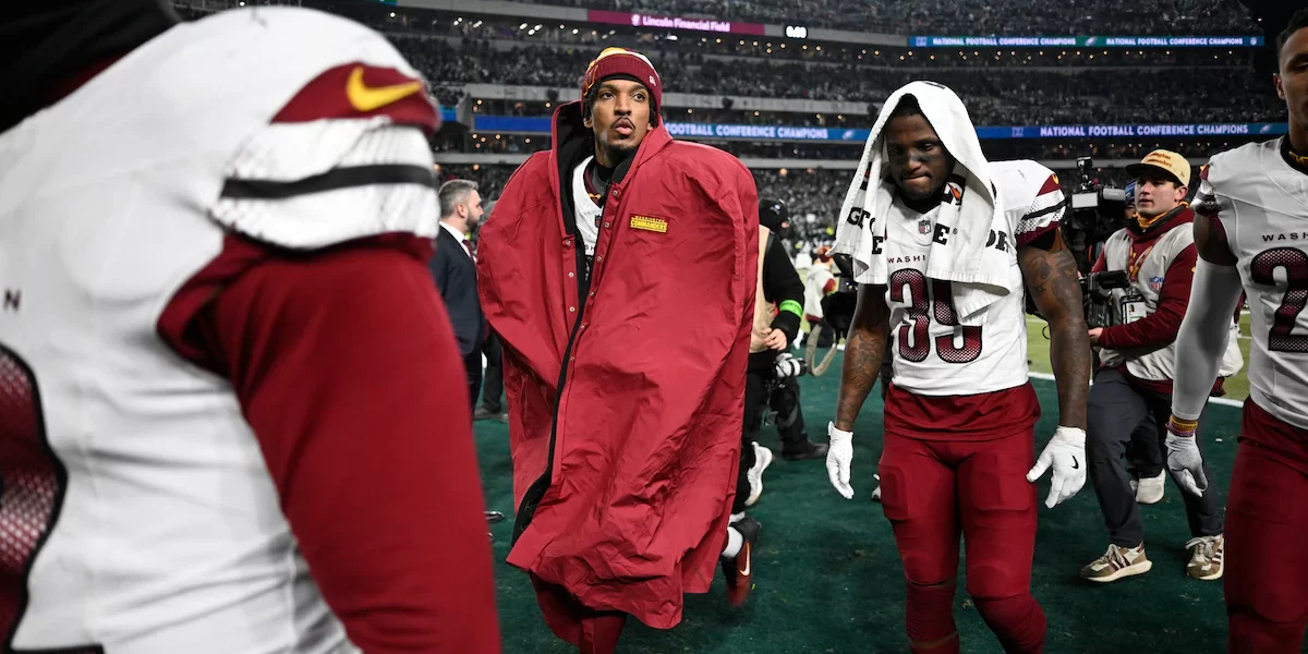 Commanders' quarterback Jayden Daniels walking back with team to locker room.