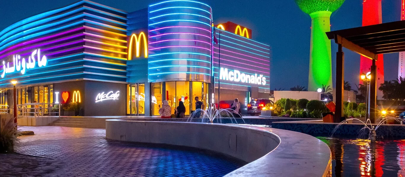 Outdoor shot of McDonald's in Kuwait City with neon blue and purple lights striped around the building