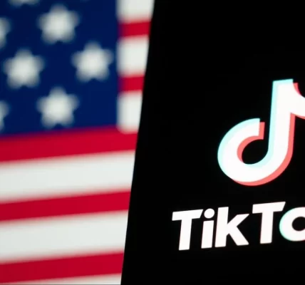 TikTok app on phone with blurred American flag in background.