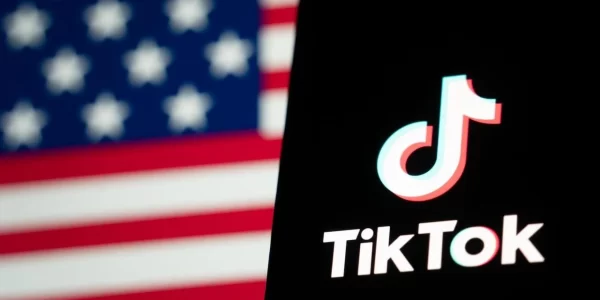 TikTok app on phone with blurred American flag in background.