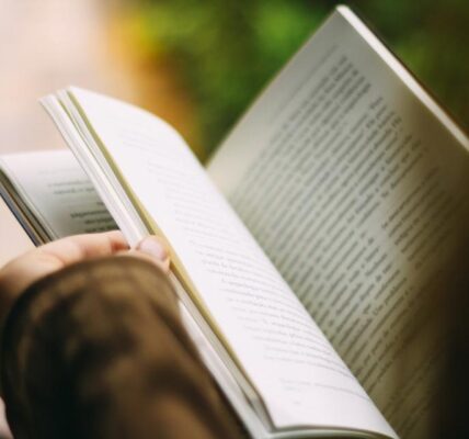 An open book with a hand holding the pages