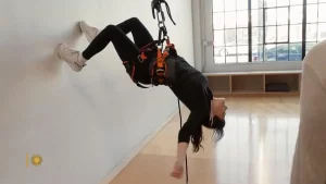 Idina Menzel attached to a harness hanging off the ceiling 