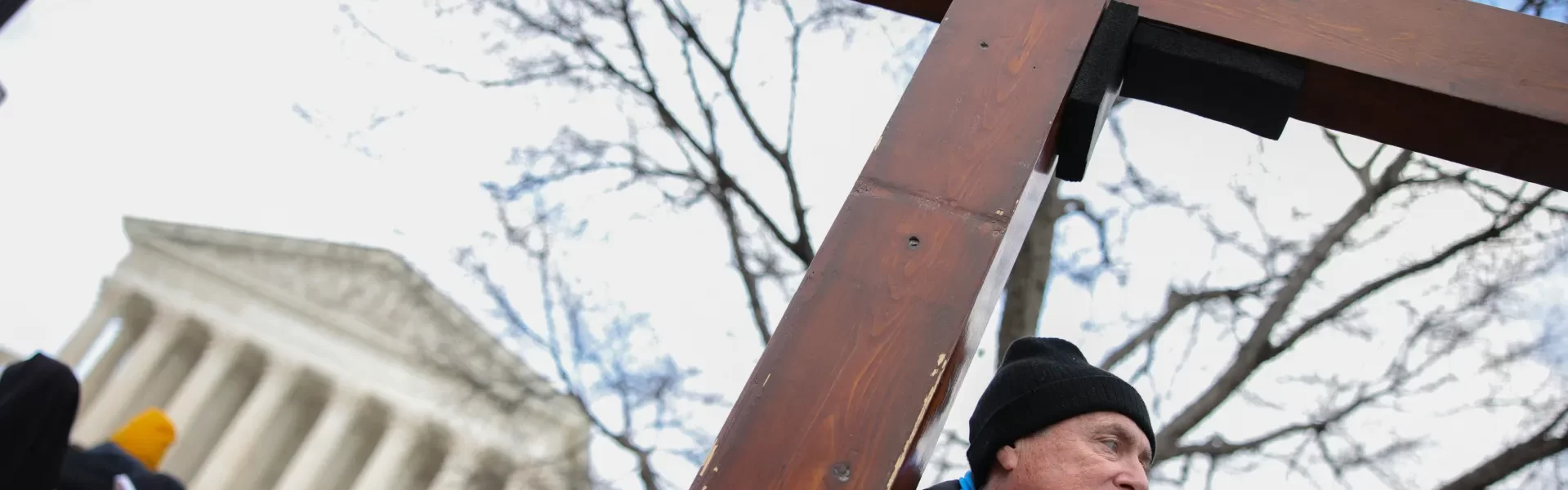 This photo depicts a man holding a cross outside of the U.S. Supreme Court building.