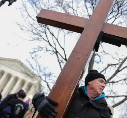 This photo depicts a man holding a cross outside of the U.S. Supreme Court building.